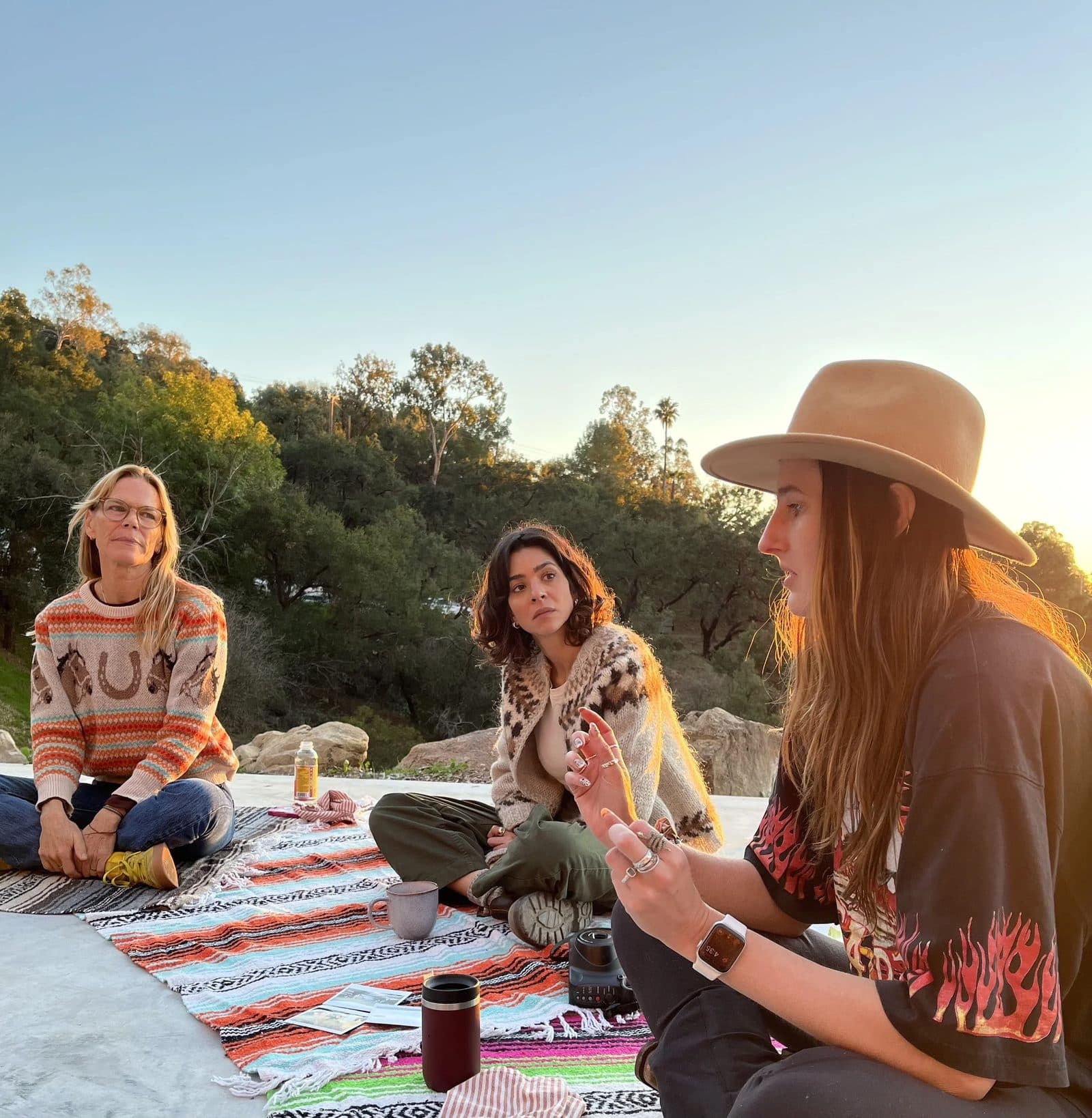 Three women sitting together at golden hour above the canyon